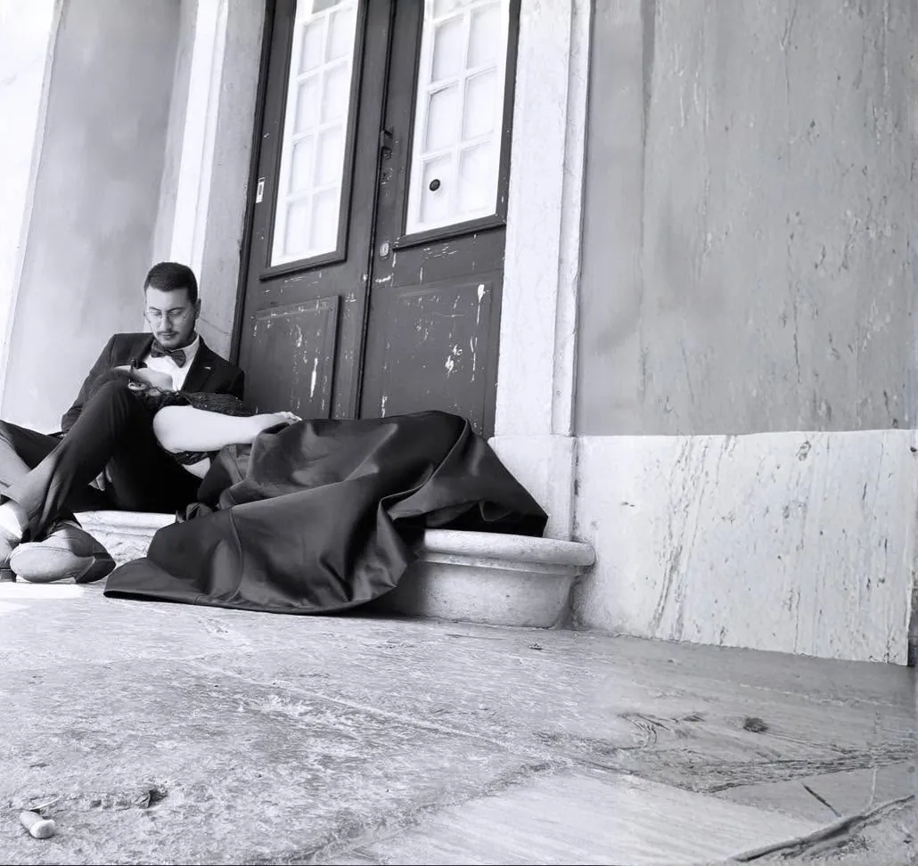 Soraia e Ricardo sentados à porta de uma casa antiga, a preto e branco